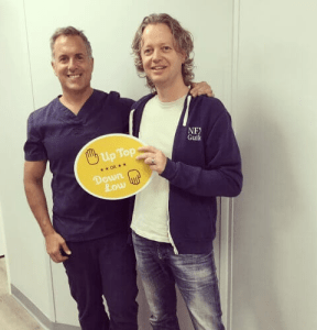 Dr. August de Oliveira with a male patient holding up top sign with man beside a man