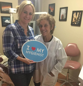 Dr. August de Oliveira with a female patient holding a I love my hygienist