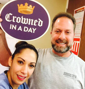 Man holding smiling while holding a crowned in a day sign