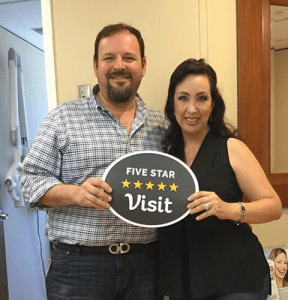 Man and woman holding five star visit sign